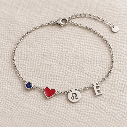 Bracelet Olianne finition argentée : pierre bleue de septembre, cœur rouge, signe Lion et initiale E