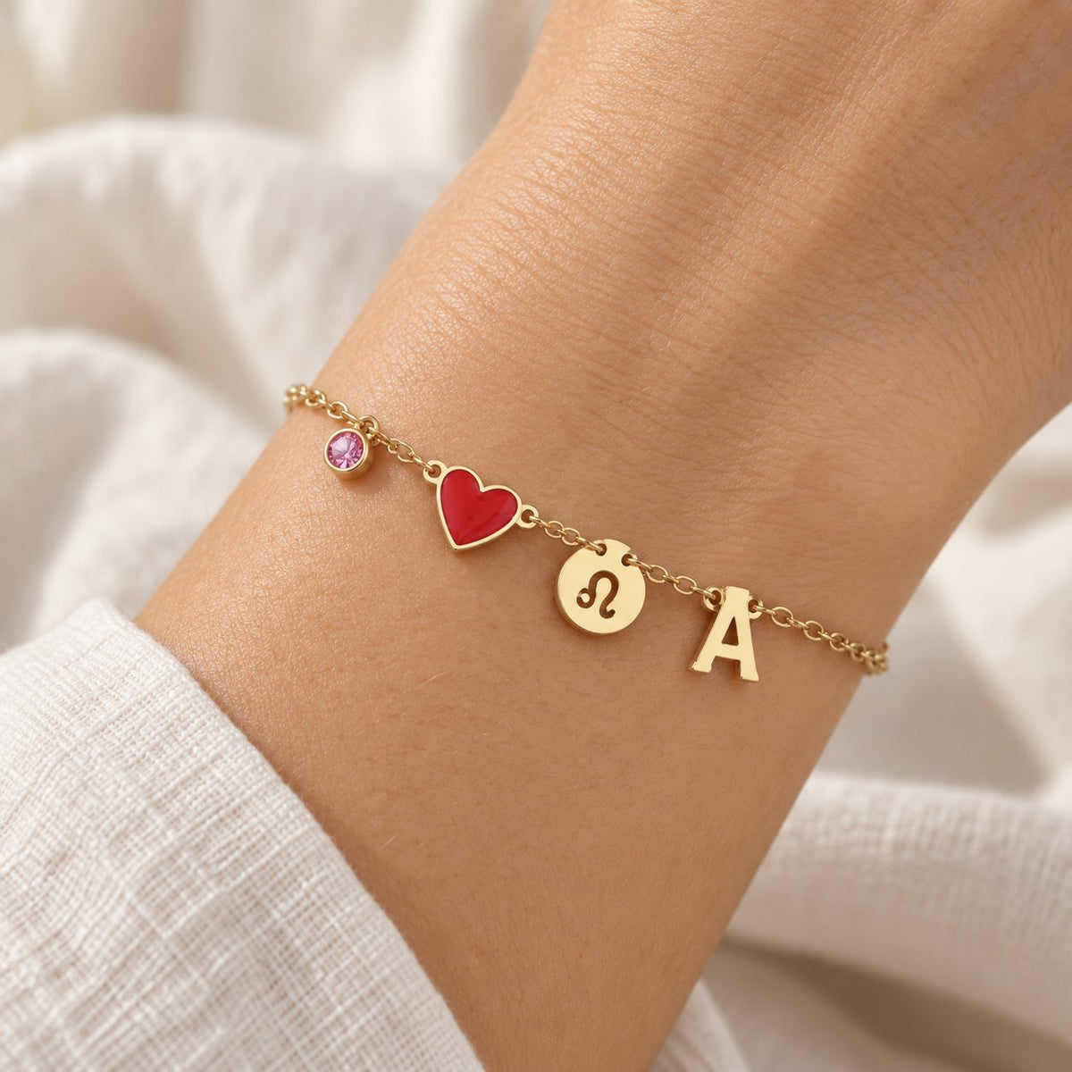Bracelet Olianne au poignet : pierre rose, cœur rouge, signe Lion et initiale A